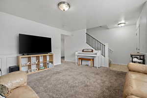 Living room featuring a textured ceiling, carpet, and stairs