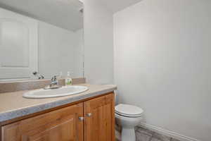 Bathroom featuring toilet, vanity, baseboards, and a textured ceiling