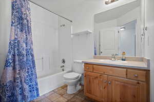 Full bathroom featuring toilet, shower / bathtub combination with curtain, and vanity