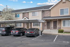 View of front facade featuring covered parking, stucco siding, and stone siding