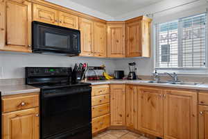 Kitchen featuring light countertops, a sink, and black appliances