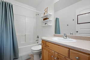 Bathroom with tile patterned flooring, toilet, shower / bath combo with shower curtain, and vanity