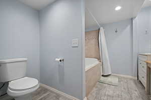 Full bath featuring toilet, vanity, baseboards, and wood tiled floor