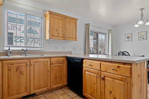 Kitchen with a peninsula, light countertops, black dishwasher, visible vents, and a sink