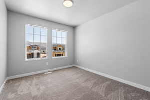 Empty room featuring visible vents, baseboards, a textured ceiling, and carpet floors