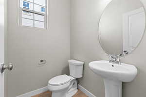 Bathroom with toilet, wood finished floors, a sink, and baseboards
