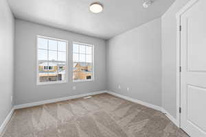 Carpeted empty room featuring visible vents, baseboards, and a textured ceiling