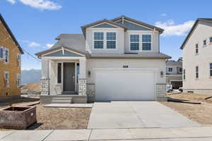 View of front of home with concrete driveway, stucco siding, stone siding, board and batten siding, and a garage