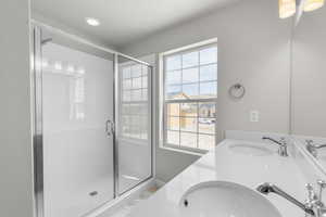 Full bathroom featuring a sink, a shower stall, and double vanity