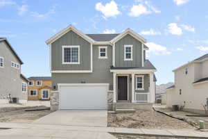 View of front of home featuring an attached garage, board and batten siding, concrete driveway, and central AC