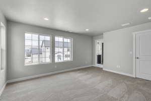 Carpeted empty room with recessed lighting, visible vents, and baseboards