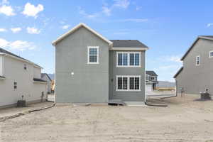 Rear view of property featuring central AC unit and stucco siding