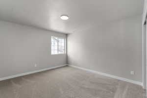 Unfurnished room featuring light carpet and baseboards