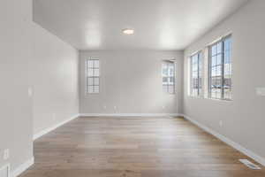 Unfurnished room featuring visible vents, light wood-style flooring, and baseboards