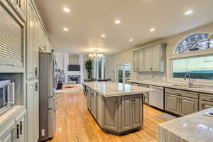 Kitchen featuring gray cabinets, a center island, a sink, and stainless steel appliances