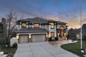 View of front facade with a front yard, a shingled roof, a garage, stucco siding, and driveway
