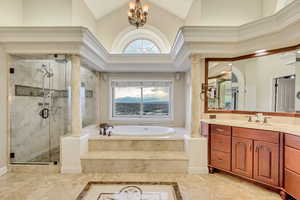 Full bath featuring a bath, a notable chandelier, decorative columns, vanity, and a stall shower