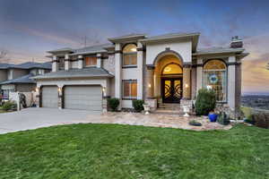 View of front of property with stucco siding, a lawn, driveway, and a chimney