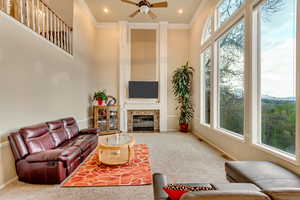Carpeted living area featuring crown molding, visible vents, a ceiling fan, and a high ceiling