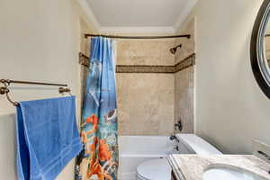 Full bath with shower / tub combo with curtain, vanity, ornamental molding, and toilet