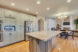 Kitchen with a chandelier, a center island, light countertops, stainless steel appliances, and arched walkways