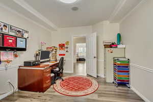 Office space featuring crown molding, light wood finished floors, and baseboards