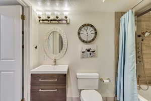 Full bathroom featuring toilet, a textured ceiling, and vanity