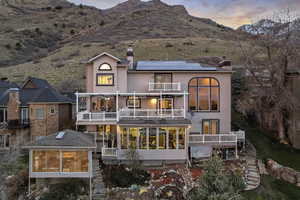 Rear view of property with a chimney, a mountain view, roof mounted solar panels, and a balcony