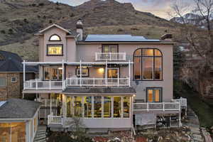 Back of house featuring a balcony, stucco siding, a chimney, and solar panels