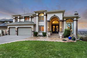 View of front of property with concrete driveway, stucco siding, a chimney, an attached garage, and a front yard