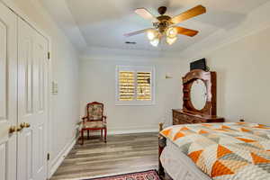 Bedroom with wood finished floors, baseboards, a ceiling fan, and visible vents