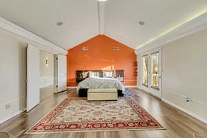 Bedroom with access to outside, wood finished floors, visible vents, and vaulted ceiling