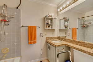 Bathroom with vanity, baseboards, shower / tub combination, crown molding, and toilet