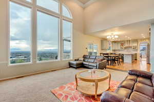 Living area featuring a wealth of natural light, a notable chandelier, light colored carpet, and visible vents