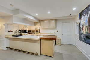 Kitchen with recessed lighting, a peninsula, wooden counters, visible vents, and a decorative wall