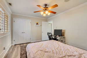 Bedroom featuring crown molding, a closet, baseboards, and wood finished floors