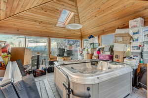 Miscellaneous room featuring light wood finished floors, a skylight, wood walls, and high vaulted ceiling