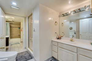 Full bathroom with toilet, shower / bathtub combination with curtain, vanity, and tile patterned flooring