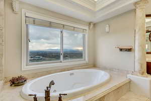 Full bathroom with ornate columns, a garden tub, and crown molding