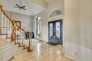 Entryway with a decorative wall, ceiling fan, a wainscoted wall, and stairs