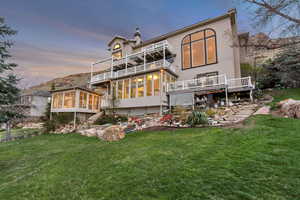 Rear view of house featuring a yard, a balcony, a sunroom, and stucco siding