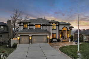 View of front of home featuring a yard, stucco siding, roof with shingles, an attached garage, and driveway