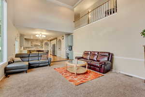 Living room with an inviting chandelier, arched walkways, light colored carpet, visible vents, and baseboards