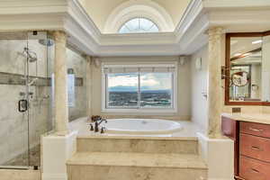 Full bathroom with ornamental molding, decorative columns, a shower stall, vanity, and a garden tub