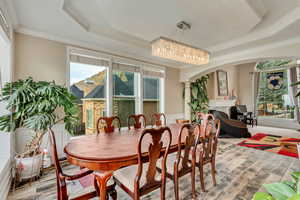 Dining room featuring ornamental molding, a fireplace, ornate columns, a raised ceiling, and arched walkways