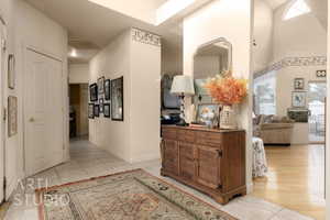 Corridor with a high ceiling, light tile patterned floors, baseboards, and visible vents