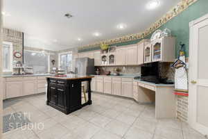 Kitchen with light tile patterned floors, glass insert cabinets, visible vents, light countertops, and decorative backsplash