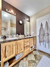 Full bathroom featuring double vanity, visible vents, a sink, and a stall shower