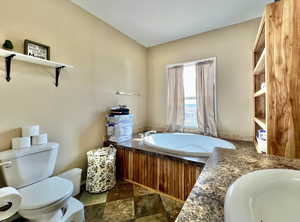 Bathroom with stone finish floor, a bath, a sink, and toilet