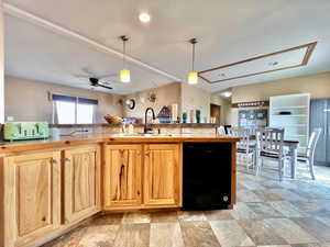 Kitchen with light countertops, decorative light fixtures, ceiling fan, dishwasher, and a sink